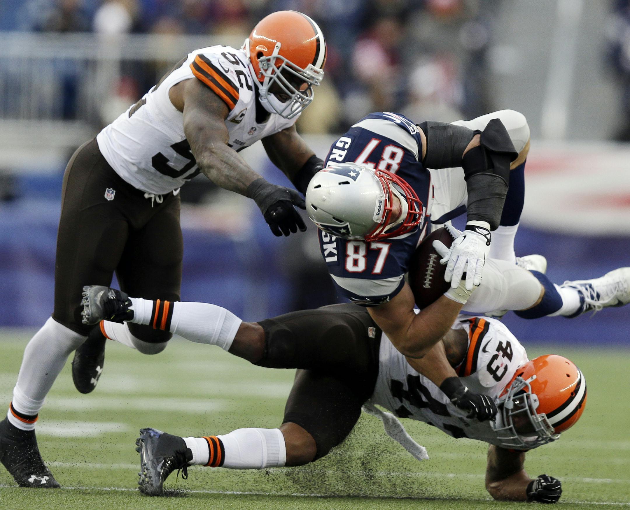 FILE - In this Sunday. Dec. 8, 2013, file photo, Cleveland Browns safety T.J. Ward (43) goes low as he hits New England Patriots tight end Rob Gronkowski (87) after a catch in the third quarter of an NFL football game in Foxborough, Mass. Joining in on the play is Browns linebacker D'Qwell Jackson (52). Gronkowski's season ended abruptly Sunday with a knee injury when he took a low hit from Ward. No penalty was called. (AP Photo/Steven Senne, File)