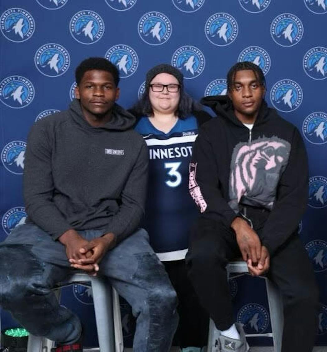 Timberwolves season-ticket holder Sabrina Hiller is flanked by Wolves players Anthony Edwards and Jaden McDaniels.