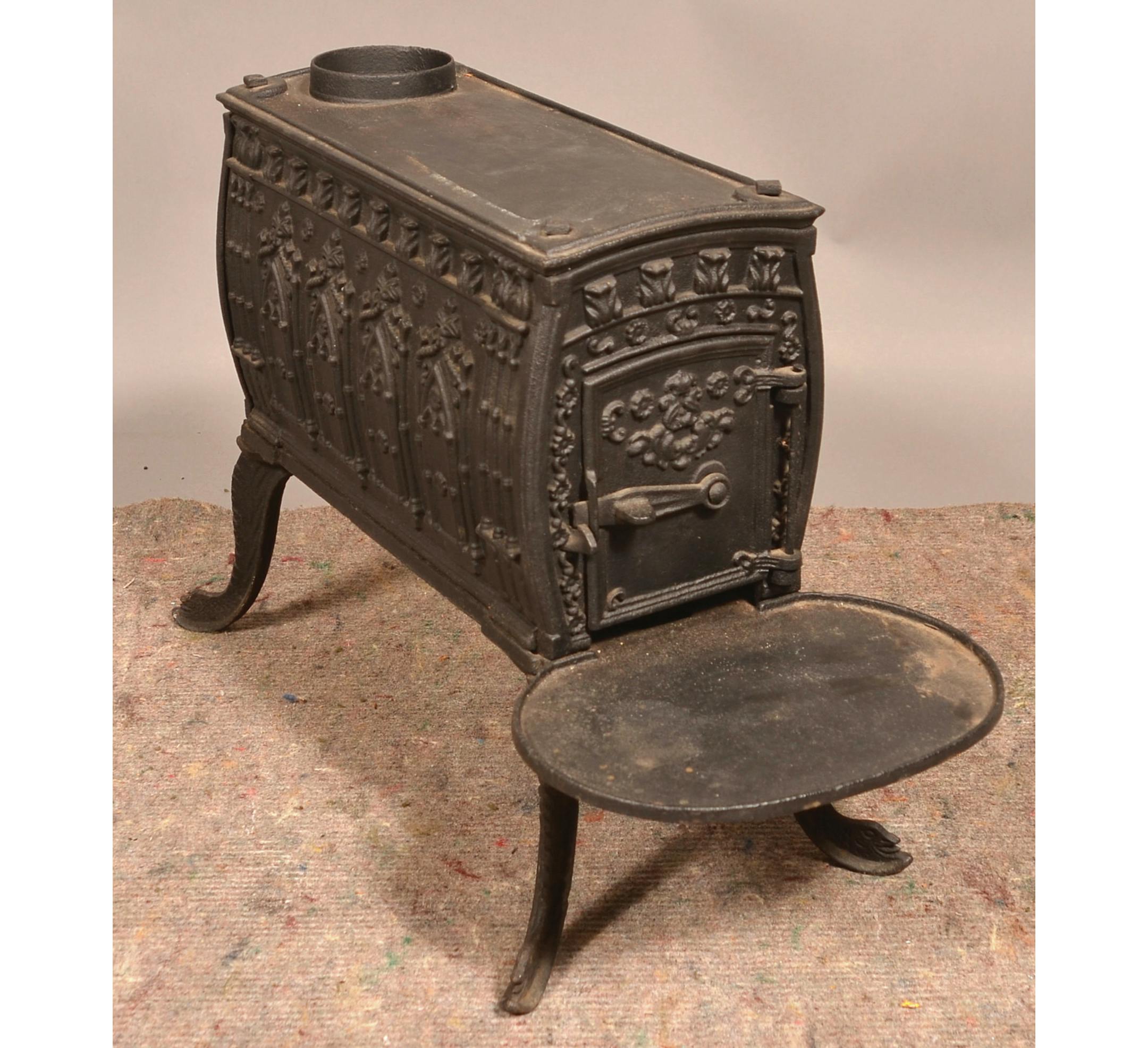 This cast-iron wood stove kept a 19th-century room warm. Its embossed designs, especially the rows of pointed arches on its sides, were meant to evoke medieval architecture.