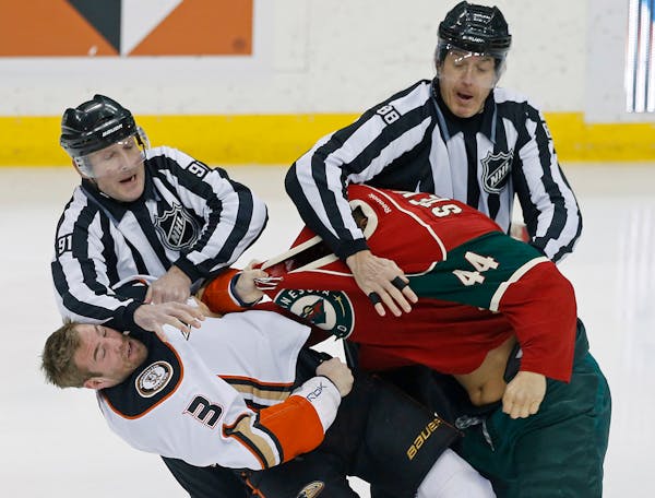 Referees Don Henderson, left, and Mike Cvik break up a fight between Anaheim Ducks� Clayton Stoner, left, and Minnesota Wild�s Chris Stewart in th