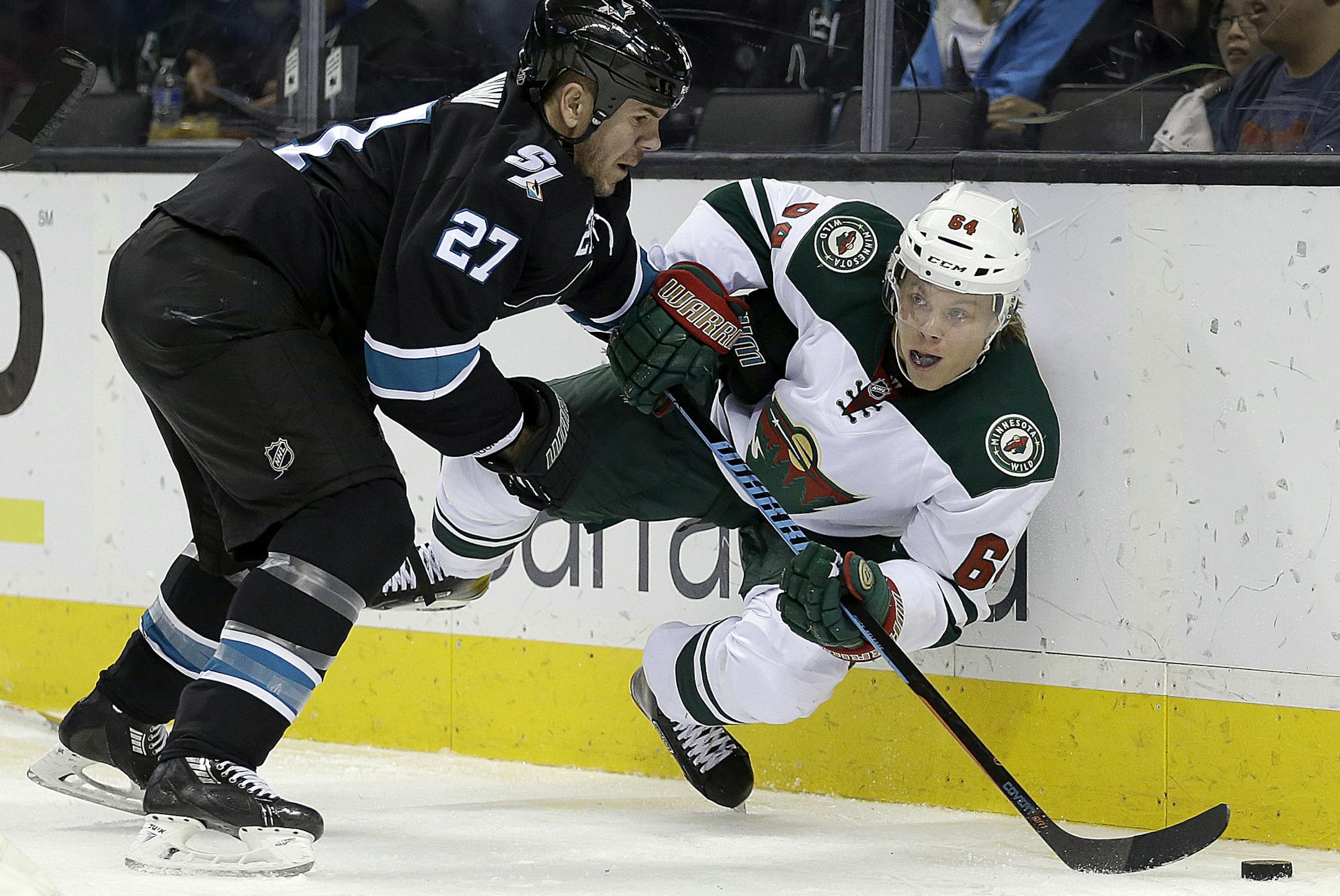 Minnesota Wild center Mikael Granlund, right, and San Jose Sharks' Scott Hannan (27) fight for the puck during the second period of an NHL hockey game Thursday, Dec. 11, 2014, in San Jose, Calif. (AP Photo/Ben Margot)