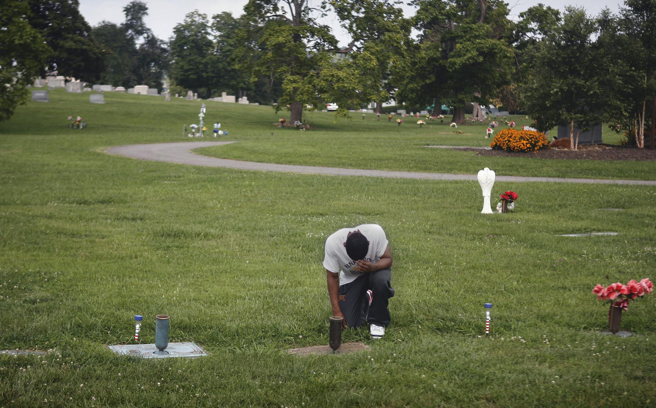 Mathieu kneels at the nameless patch of grass where his best friend is buried, in New Gray Cemetery in Knoxville. Phillip "Tookie" Stanford took his life after all of his immediate family passed away: his 5-year-old sister shot in gang violence, his father killed while being robbed and his mother passing away from Leukemia. The three of them are buried side by side perpendicular to Tookie's grave, which has no headstone. [ 891693 Like every summer, DeAndre Mathieu, the Minnesota mens basketballl