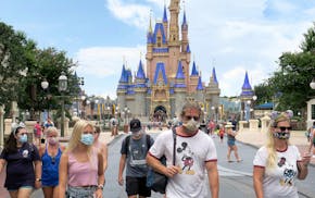 In this file photo, guests wear masks, as required, to attend the official re-opening day of the Magic Kingdom at Walt Disney World on July 11, 2020.