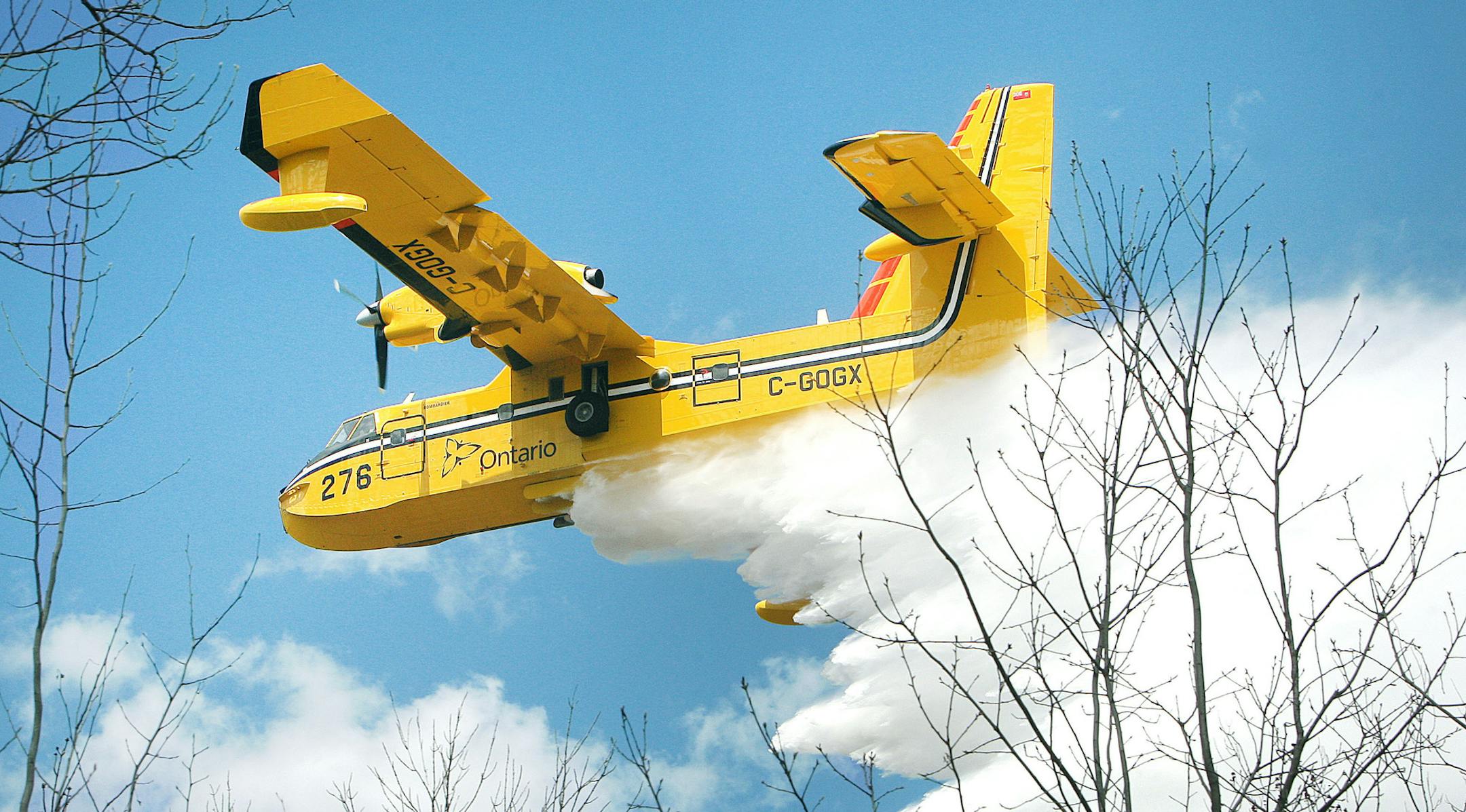 A Bombardier 415 water bomber operating out Ontario dumps a load water on a fire along East Beauregard Lake Road Wednesday afternoon, May 15, 2013 near Barnes, Wis. Authorities are investigating whether logging operations may have sparked a massive wildfire in northwestern Wisconsin that destroyed dozens of buildings and forced at least 60 people from their homes, state officials said Wednesday. (AP Photo/The Duluth News-Tribune, Bob King)