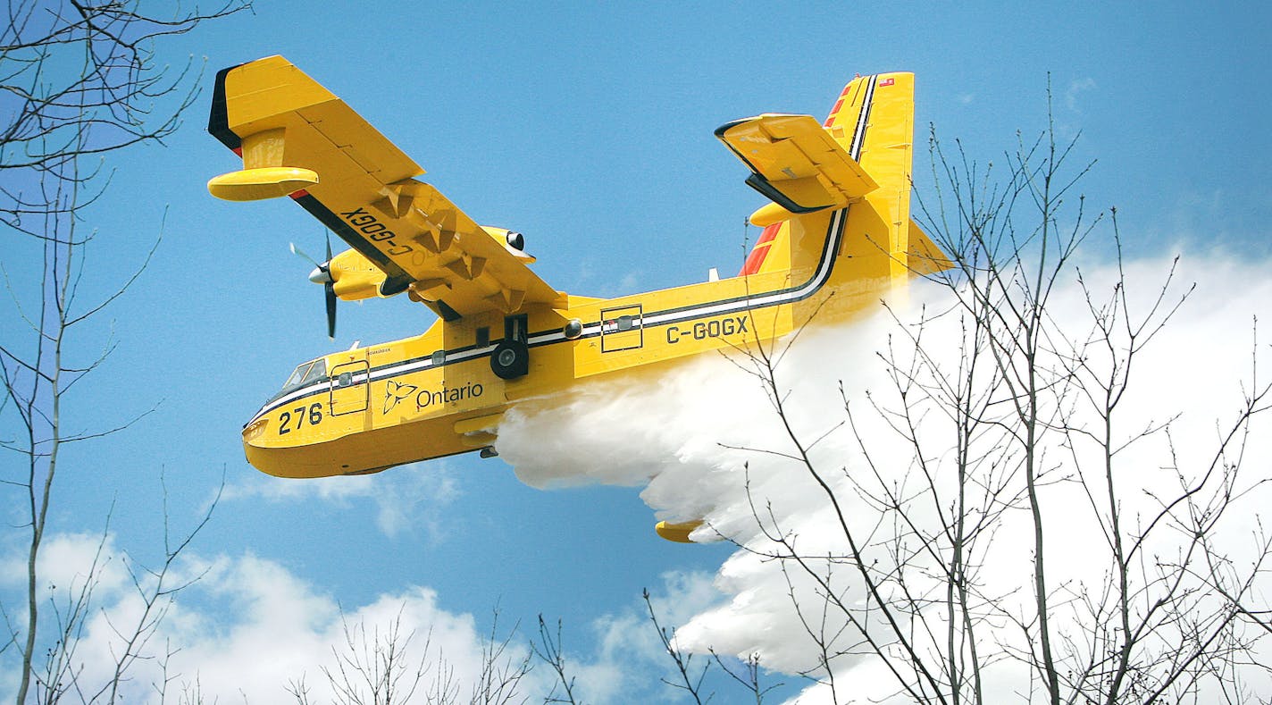 A Bombardier 415 water bomber operating out Ontario dumps a load water on a fire along East Beauregard Lake Road Wednesday afternoon, May 15, 2013 near Barnes, Wis. Authorities are investigating whether logging operations may have sparked a massive wildfire in northwestern Wisconsin that destroyed dozens of buildings and forced at least 60 people from their homes, state officials said Wednesday. (AP Photo/The Duluth News-Tribune, Bob King)