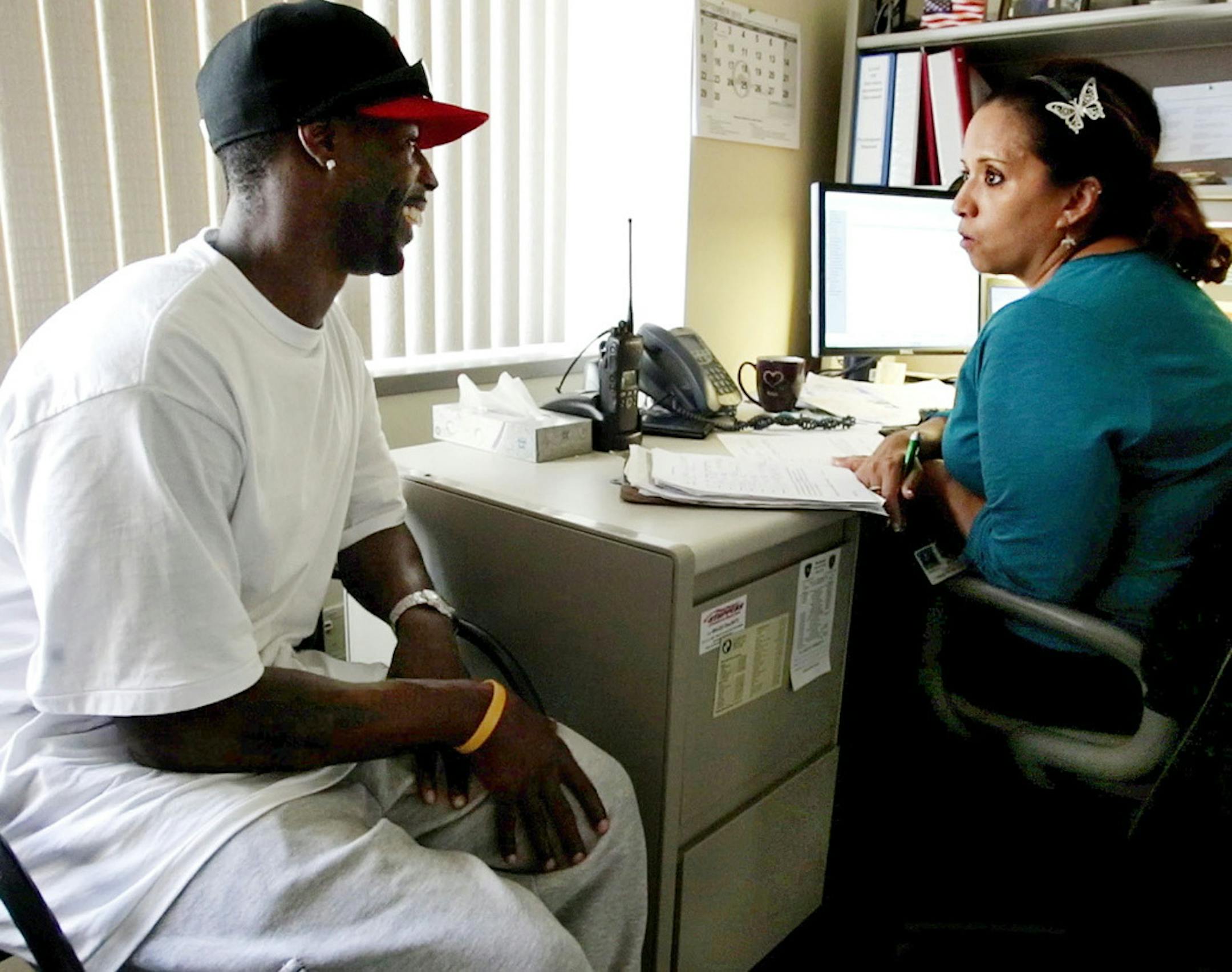 FOR RELEASE MONDAY, DECEMBER 30, 2013, AT 12:01 A.M. CST - In this Aug. 31, 2013 photo, Tim Gayles, of Rochester, Minn. goes over his schedule with his Olmsted County parole officer Robyn Wood at the Government Building in Rochester, Minn. Originally from South Chicago, Gayles wants his children to grow up in a better environment than he did. "Kids don't do as we say. They do as they see us do," he said. (AP Photo/The Rochester Post-Bulletin, Joe Michaud-Scorza)
