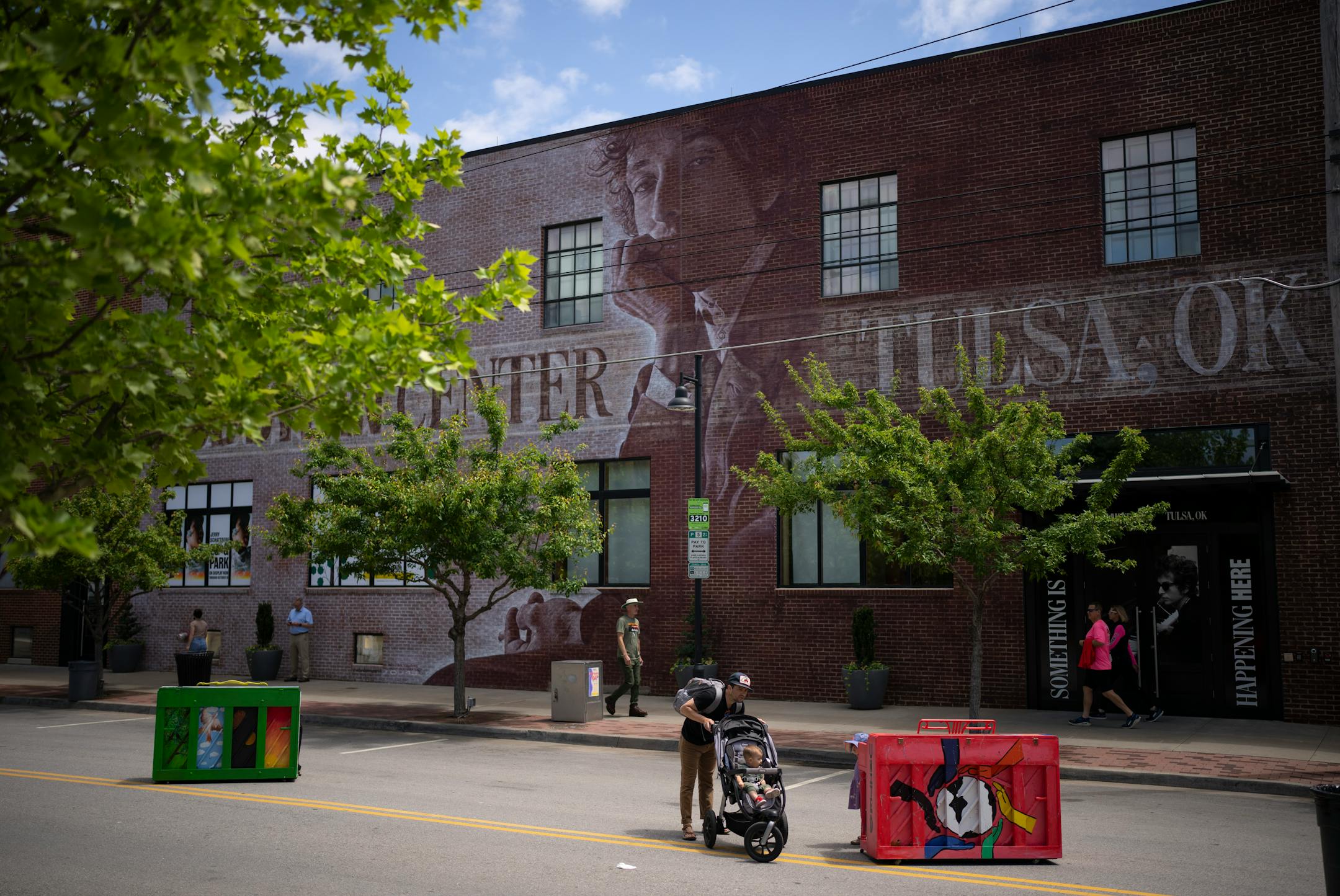 The exterior of the Bob Dylan Center features a mural based on a 1965 photograph by Jerry Schatzberg. The pianos and pedestrians on the street in front of the center were part of Mayfest, Tulsa's annual arts festival.