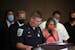 Chisholm Police Chief Vern Manner reads remarks from Nancy Daugherty's daughter, Gina Haggard (right), joined by her husband Dave Haggard, as BCA Supe