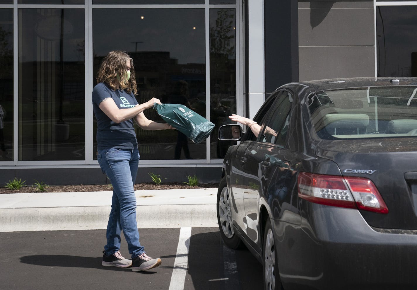 Schuler Shoes assistant manager Siobhan Morin brought out a pair of shoes to customer Melissa Werra at curbside pickup outside the store in Maple Grove, Minn., on Thursday, May 14, 2020. On Monday this store is one of many around Minnesota that will open its showroom at 50 percent capacity to customers. ] RENEE JONES SCHNEIDER • renee.jones@startribune.com