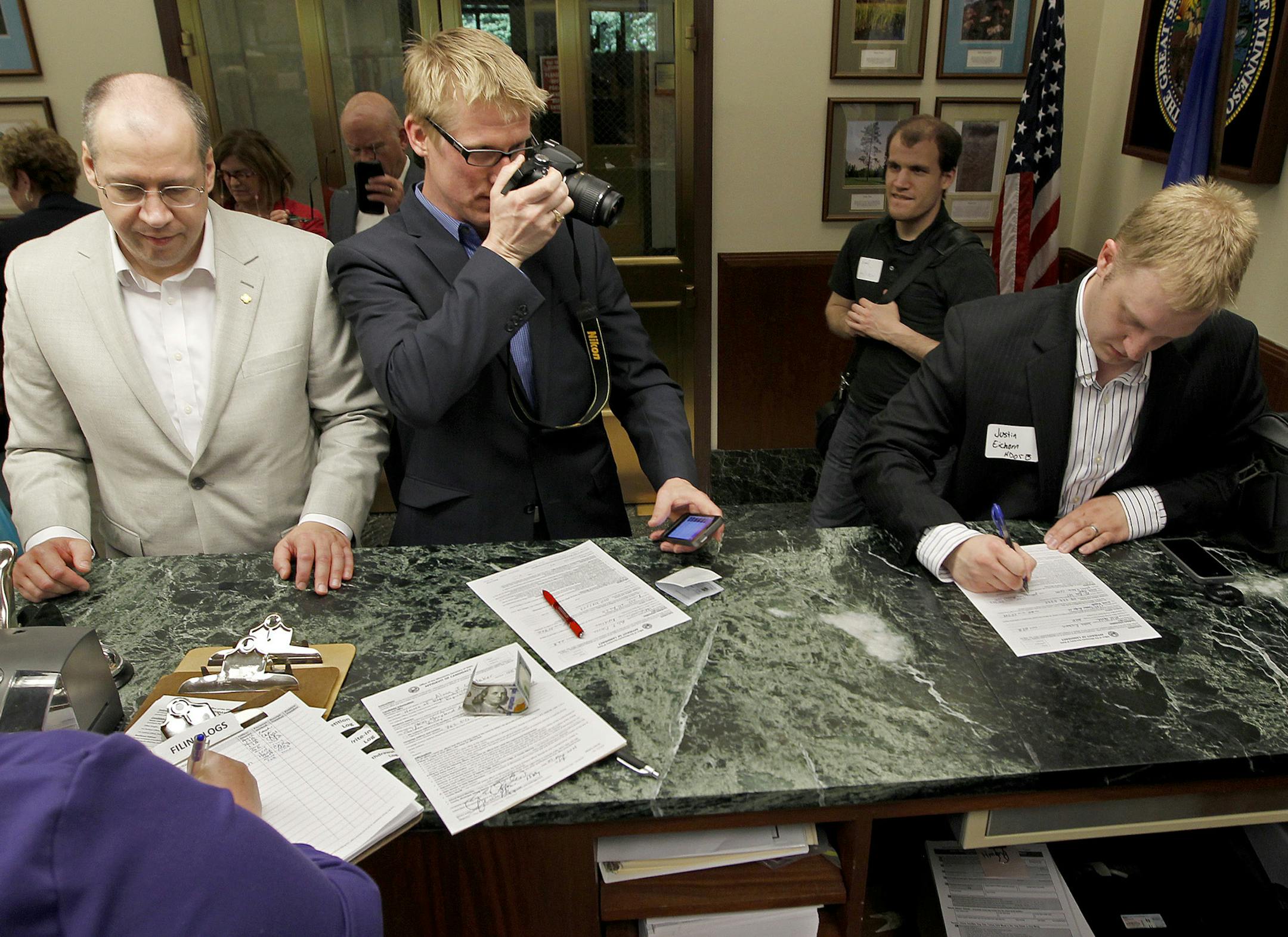 As House Republican candidate Alma Wetzker, left, filed for office, Nels Pierson, center, grabbed a shot of candidate Justin Eichorn, right, as they joined other candidates filing for office at the Office of the Secretary of State, Thursday, May 29, 2014 in St. Paul, MN. ] (ELIZABETH FLORES/STAR TRIBUNE) ELIZABETH FLORES • eflores@startribune.com