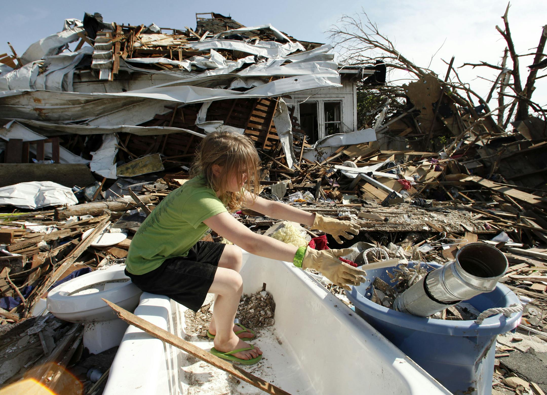 Laura Cobb, 11, cleans debris from a bathtub while helping with clean-up at her destroyed home in Joplin, Mo. Monday, May 30, 2011. Four members of her family escaped injury by seeking refuge in the tub when an EF-5 tornado tore through much of the city May 22, damaging a hospital and hundreds of homes and businesses and killing at least 139 people. (AP Photo/Charlie Riedel)
