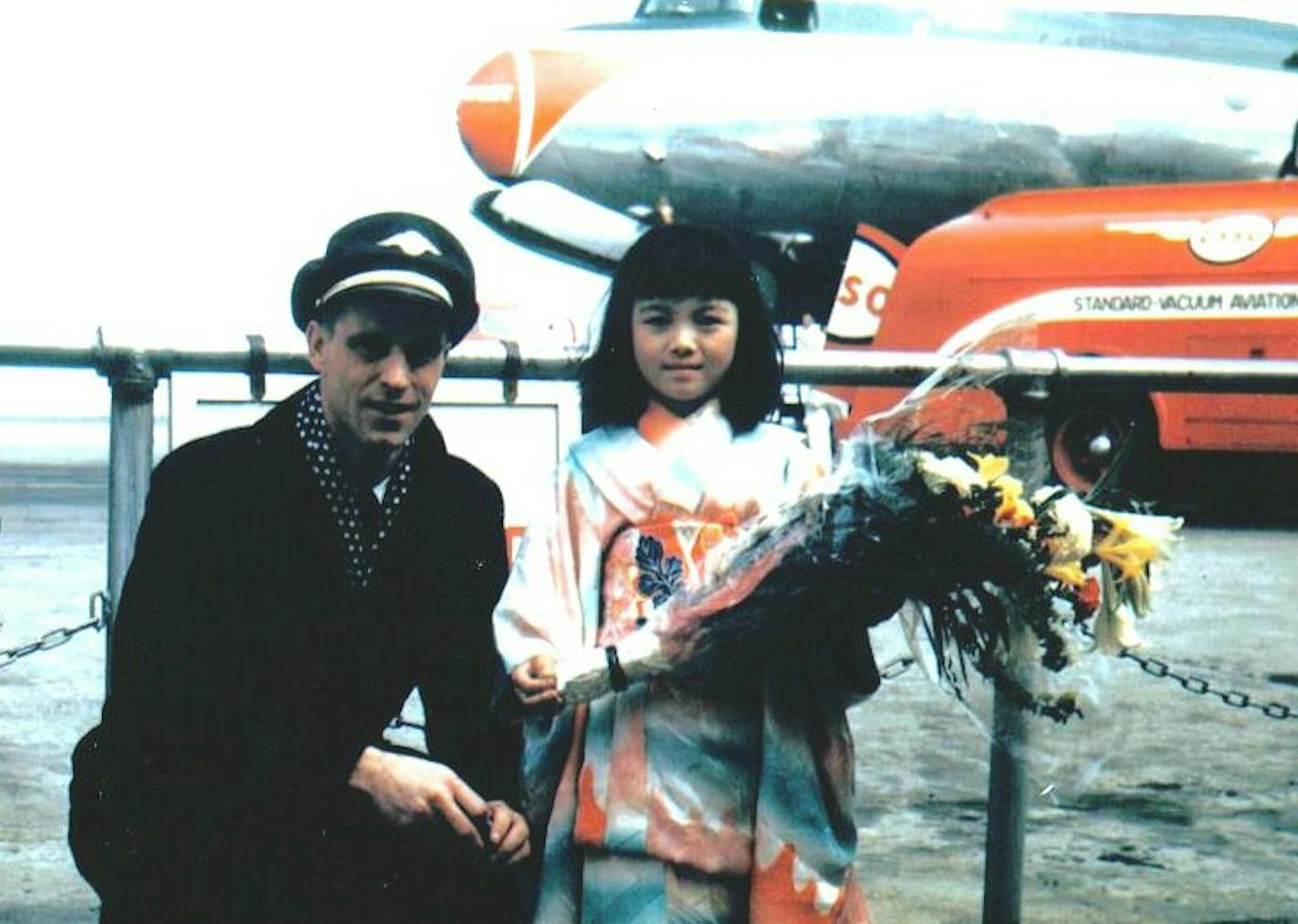 Jerome Koerner, the radio operator on Northwest's first passenger flight to Tokyo in 1947, was welcomed by a little Japanese girl upon arrival. The DC4 that made the flight is behind them.