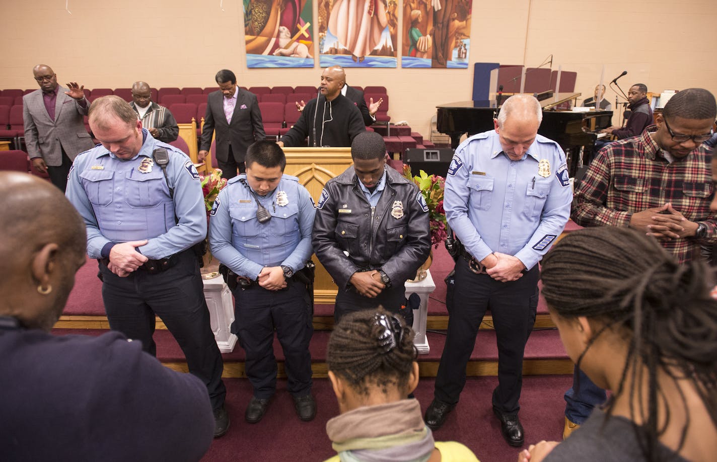 From left, 4th Precinct police officers Will Gregory, Roger Moua, Xavier Rucker and Inspector Mike Friestleben, bowed their head during a prayer recognizing police lead by the Rev. Jerry McAfee at the end of Wednesday night's service. ] (AARON LAVINSKY/STAR TRIBUNE) aaron.lavinsky@startribune.com The Rev. David Keaton of Fellowship Missionary Baptist Church, the Rev. Jerry McAfee and many other faith leaders met for an evening of prayer and dialogue regarding the 4th Precinct Protests with commu