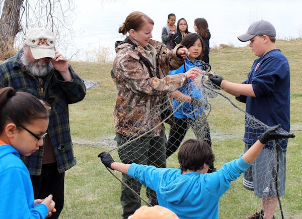 Young students who are members of the Bois Forte Band of Chippewa living near Lake Vermilion learn about fish netting as part of their education that 