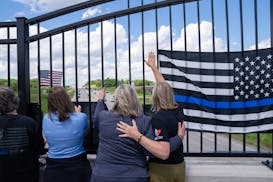 Tammy Erickson and Lisa Fobbe embrace as they watch the procession from an overpass of I-494. 