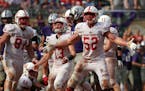 St. John's University defensive lineman Nathan Brinker (52) celebrated after University of St. Thomas running back Josh Parks (26) was pulled down by 