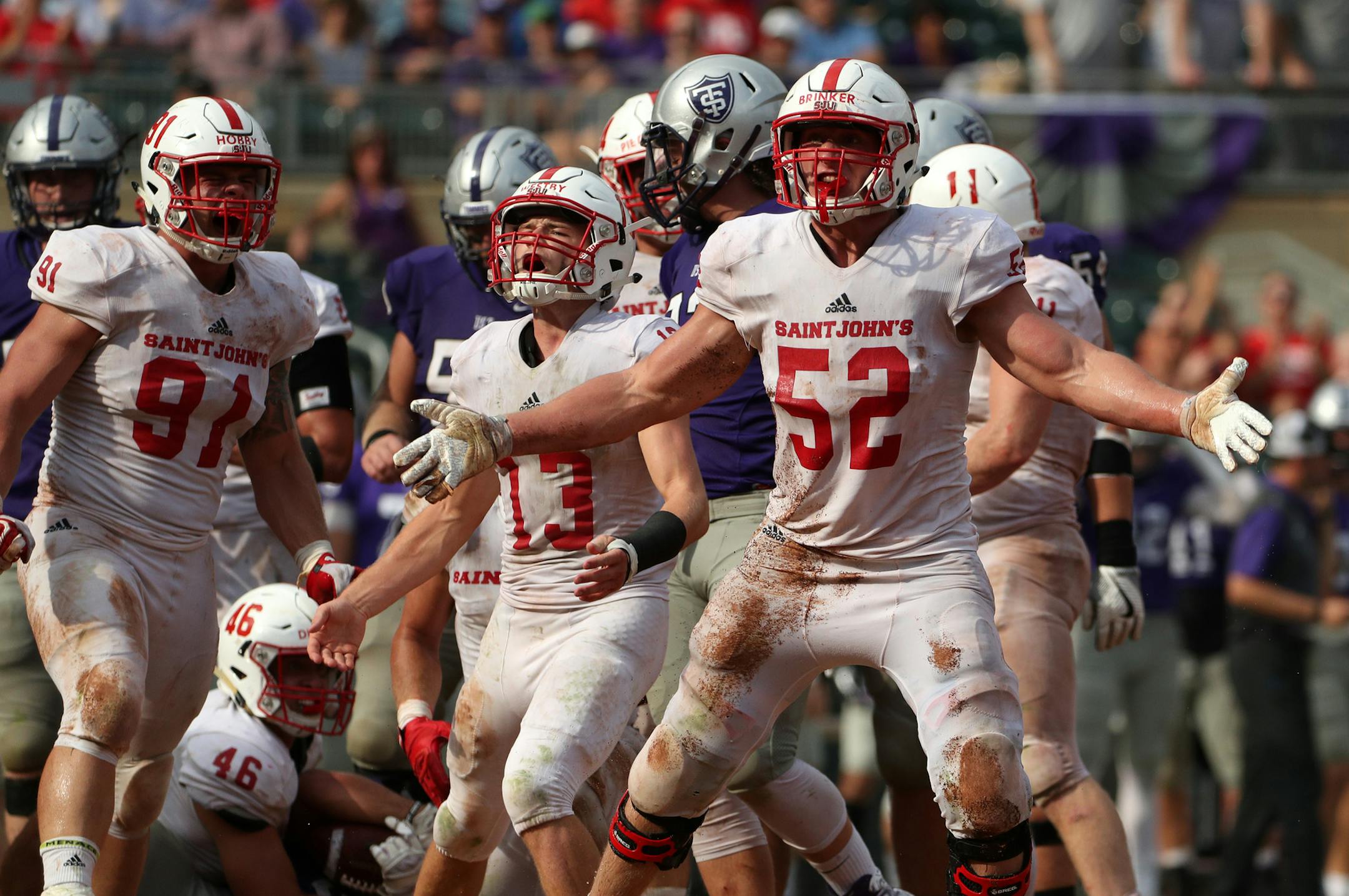 St. John's University defensive lineman Nathan Brinker (52) celebrated after University of St. Thomas running back Josh Parks (26) was pulled down by St. John's University defensive lineman Trevor Dittberner (46) earlier this season.
