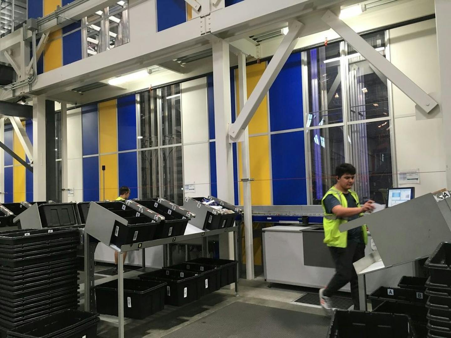 A Best Buy worker at the Compton, Calif., facility receives merchandise that has been picked by robots, and loads them into bins to be packaged shipped out to customers within a few hours.