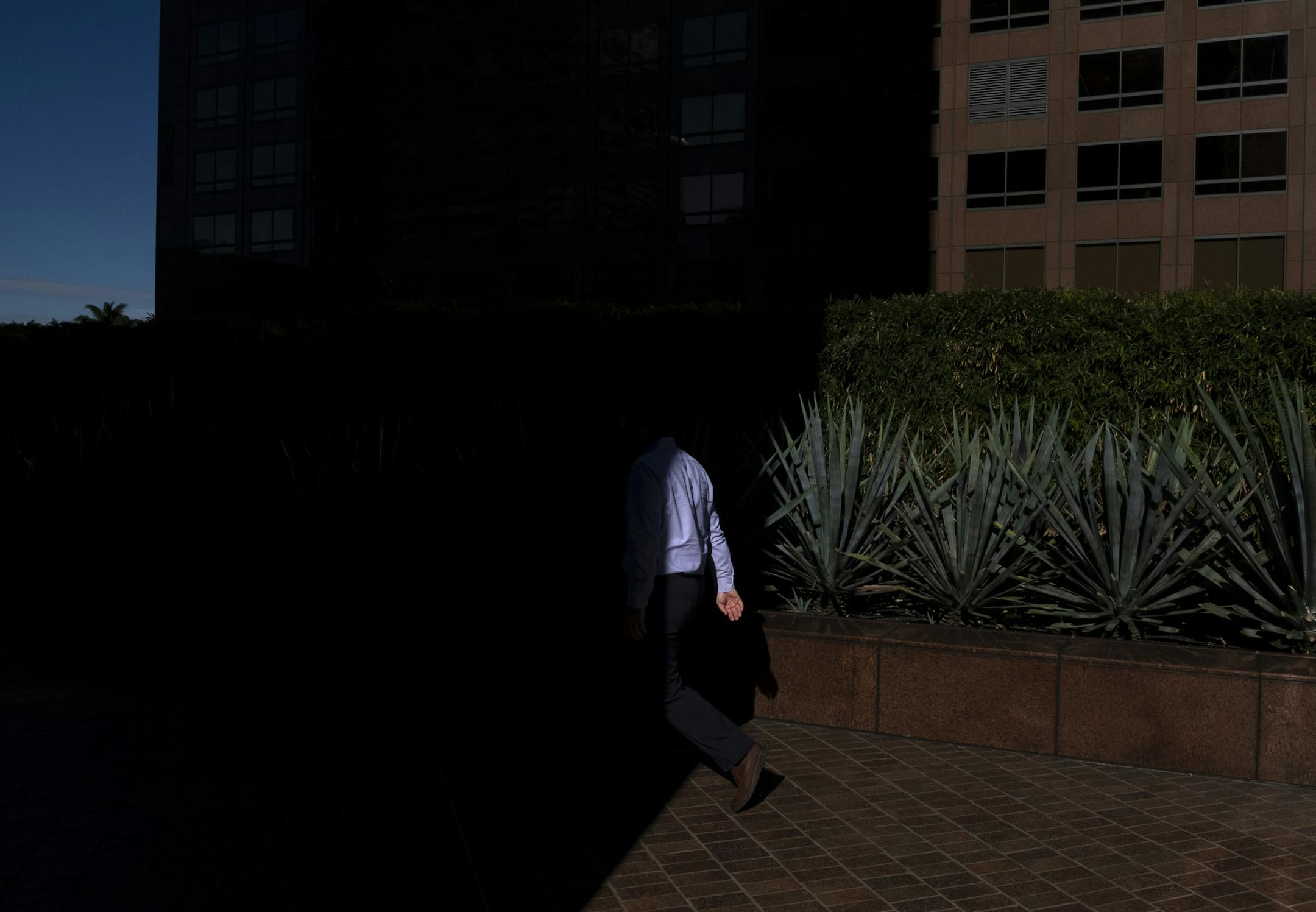 FILE- In this Dec. 4, 2018, file photo a man walks into the shade of a building in downtown Los Angeles. When deciding whether to buy, skip or toss an item, minimalists try to determine whether it adds value to their lives. Apply minimalism to your financial life, and you can shed outdated obligations and reduce stress. (AP Photo/Jae C. Hong, File)