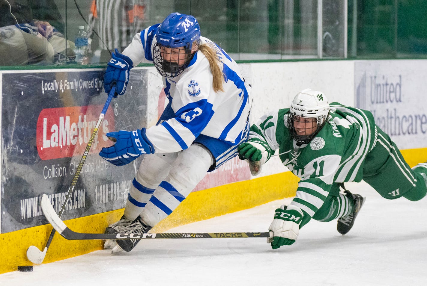 Minnetonka forward Lindzi Avar (13) carries the puck past Holy Family defender Ella Knewtson (11) during the first period of the Class 2A Section 2 girl's hockey championship Friday, Feb. 17, 2023 at Braemar Arena in Edina, Minn. ]