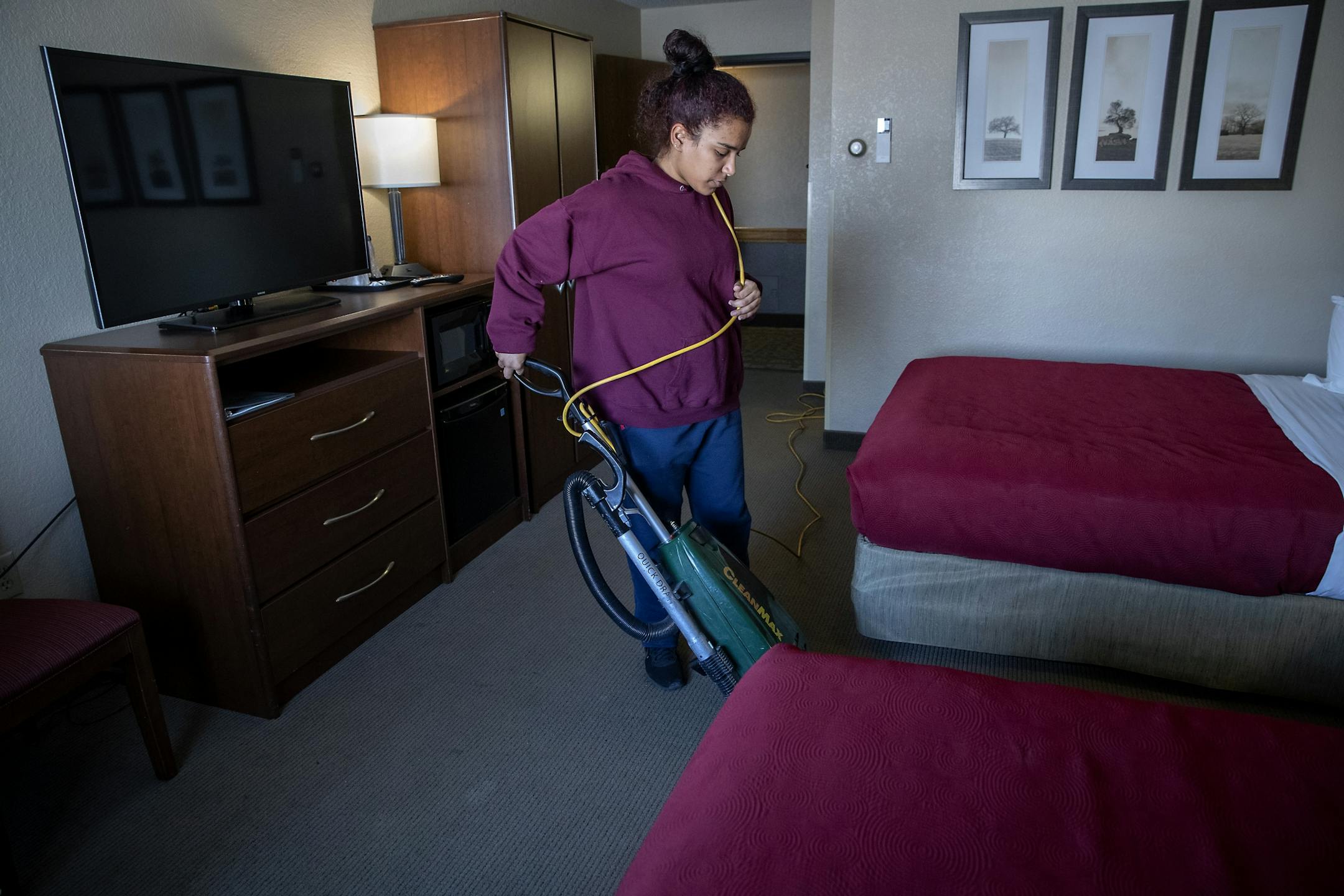 Elianeth Bastardo, 18, who has completed a course to become a CNA, vacuumed a hotel room during her shift at the Americinn, Tuesday, February 18, 2020 in Roseau, MN.