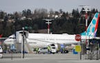 Workers walk next to a Boeing 737 MAX 8 airplane parked at Boeing Field, Thursday, March 14, 2019, in Seattle. The fatal crash Sunday of a 737 MAX 8 o