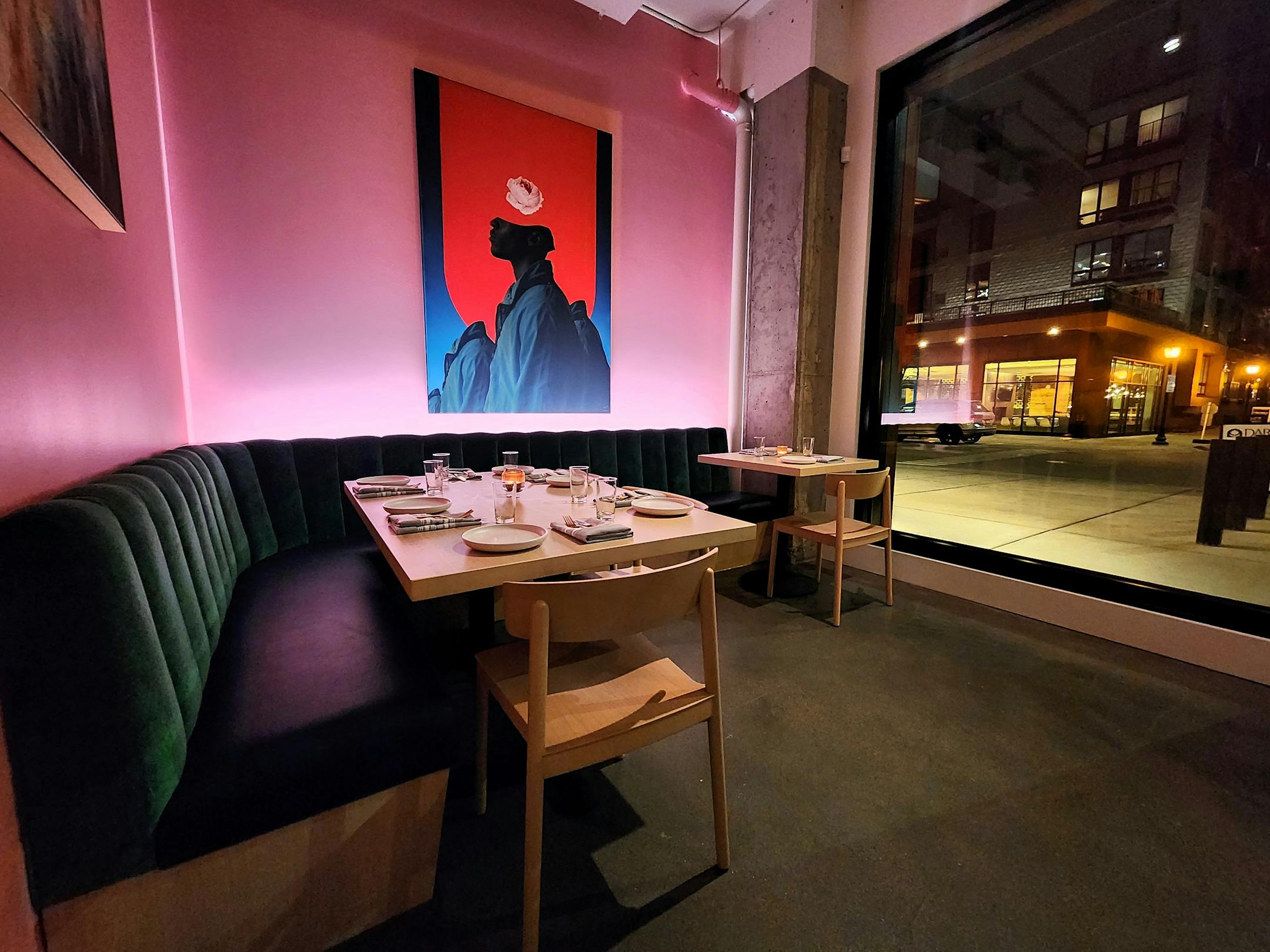 A green banquette in front of a pink wall with art on it