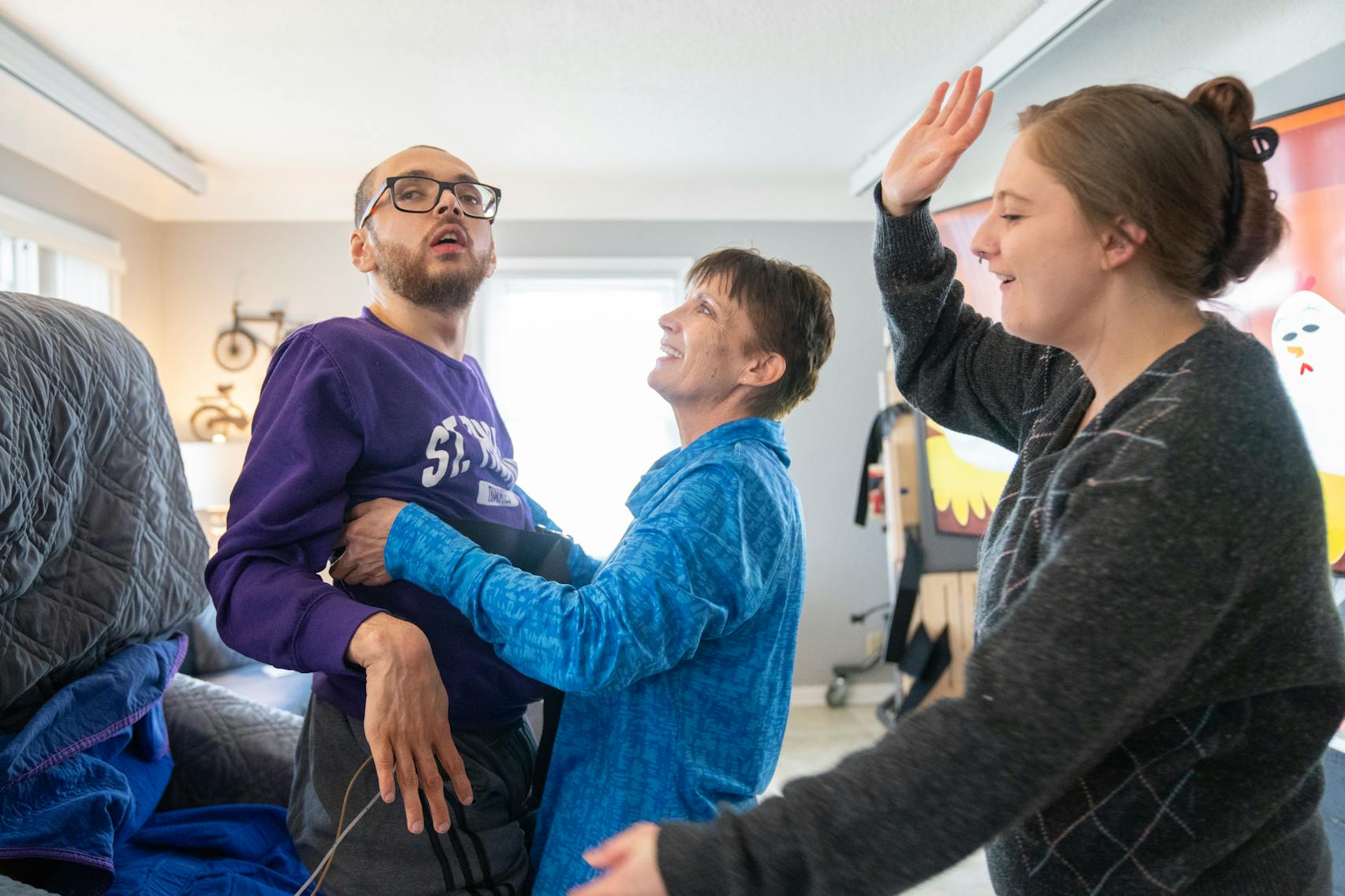 Physical therapist Lori McCoy helps Kylen Ware during therapy, which he has once a week, as Ashley Topp, a community inclusion specialist, offers a high-five in praise of his efforts.