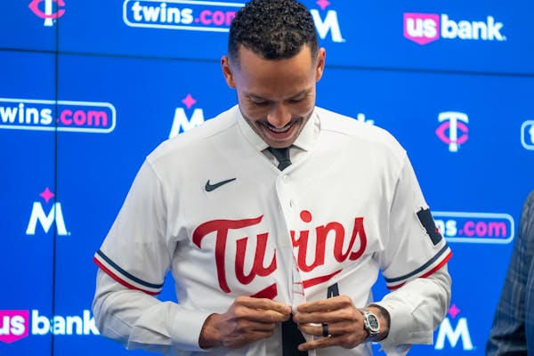 Minnesota Twins shortstop Carlos Correa tries on a new uniform during a press conference.