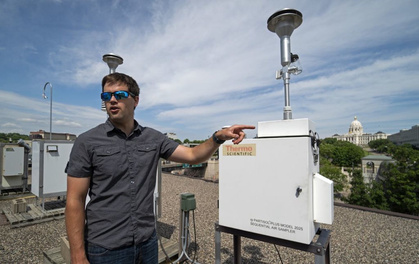 PCA's Jerrod Eppen shows some of the sampling equipment on top of a building near the Capitol.