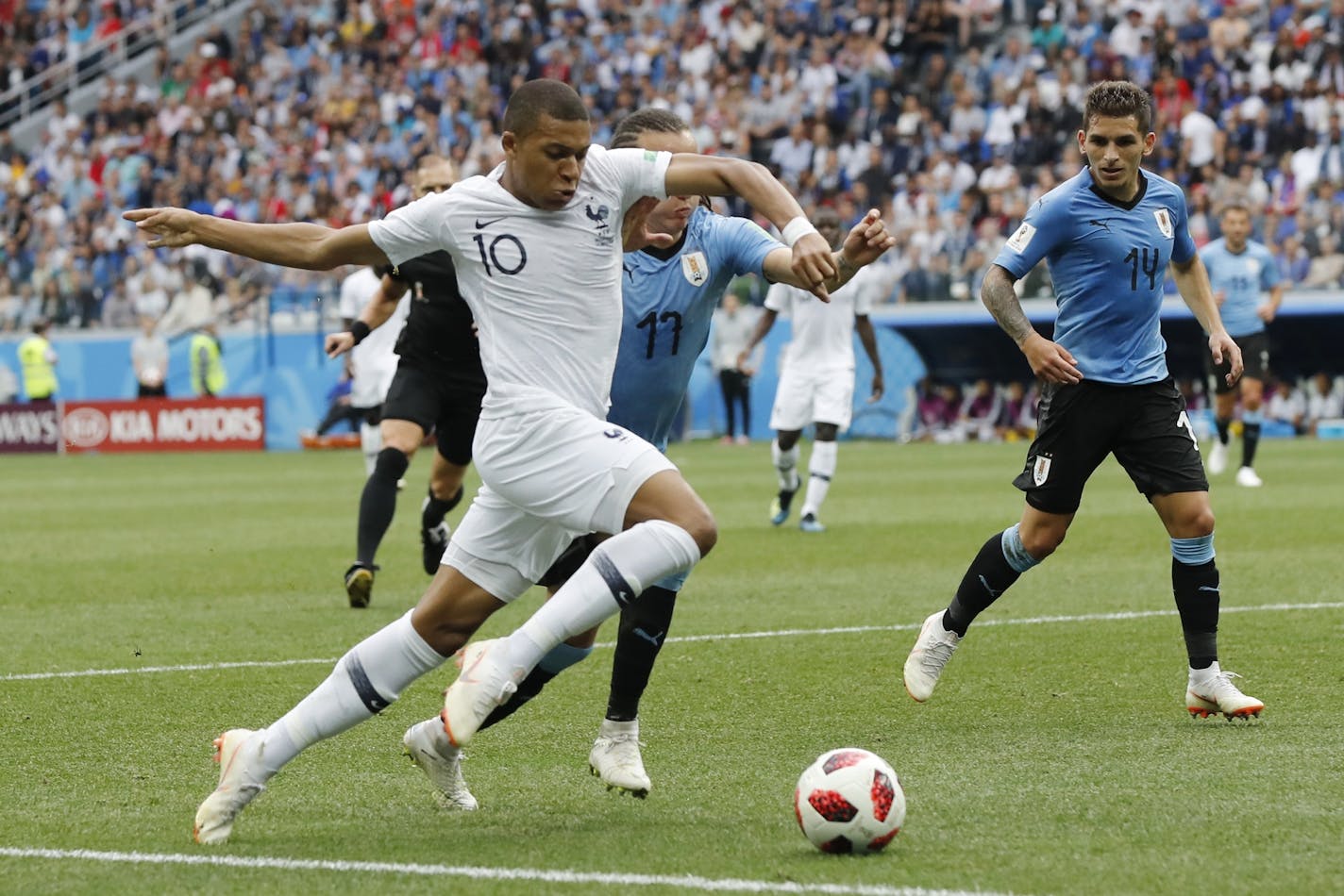 France's Kylian Mbappe, left, and Uruguay's Diego Laxalt, center, challenge for the ball during the quarterfinal match between Uruguay and France at the 2018 soccer World Cup in the Nizhny Novgorod Stadium, in Nizhny Novgorod, Russia, Friday, July 6, 2018. (AP Photo/Petr David Josek)