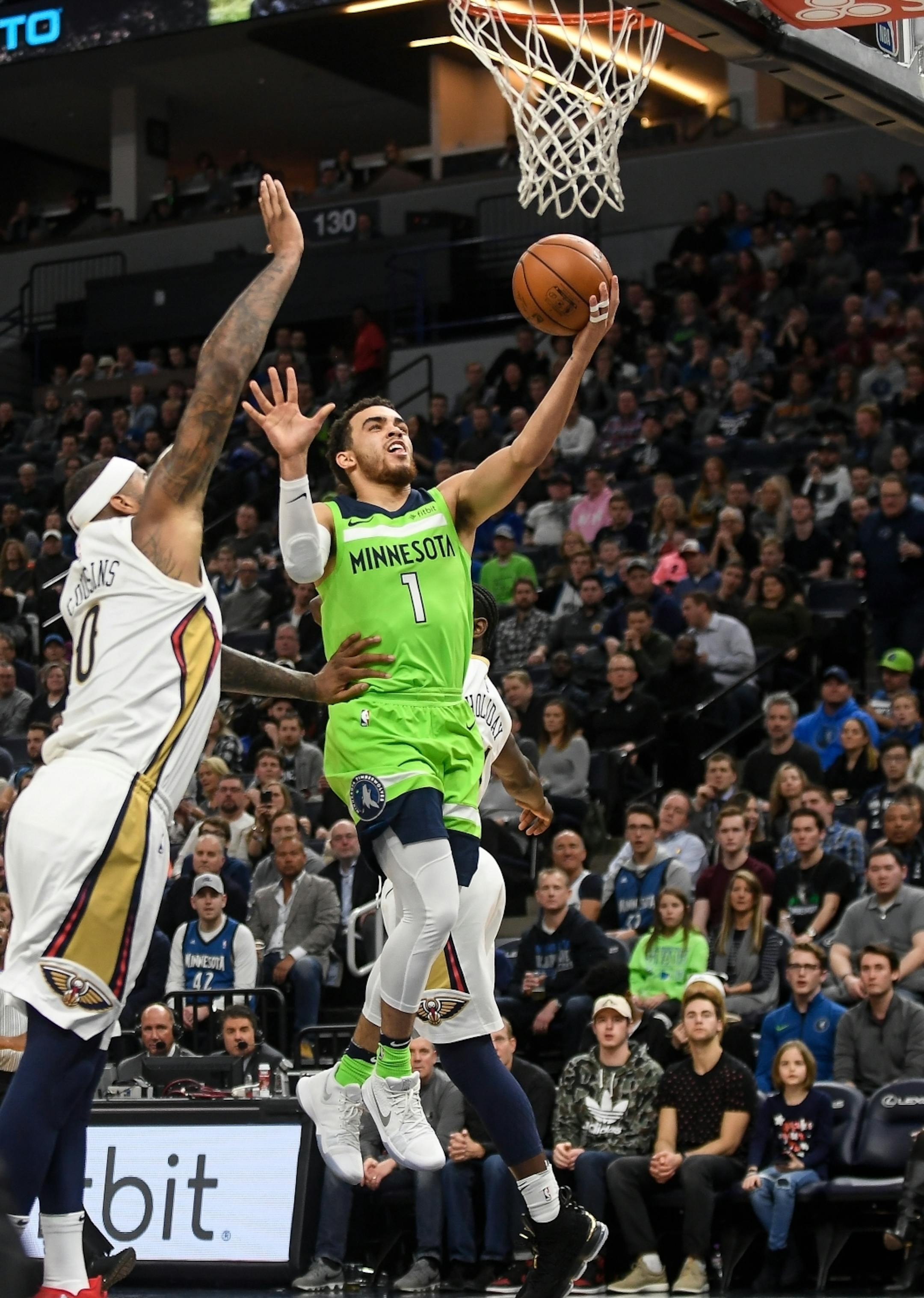 Minnesota Timberwolves guard Tyus Jones (1) scored a layup despite defensive efforts by New Orleans Pelicans center DeMarcus Cousins (0) in the second quarter.