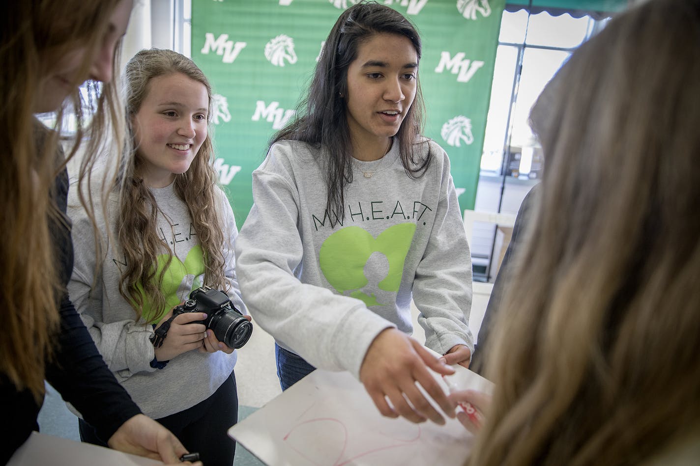 Mounds View High students Hannah Berndt, left, and Sanjana Dutt, center, from H.E.A.R.T - Helping Every At-Risk Teen - organized a wellness week by handing out Kind bars to remind students to be kind to each other and set up a photo booth with kids answering the question: "how do you practice wellness," in the school's cafeteria, Friday, April 27, 2018 in Arden Hills, MN.