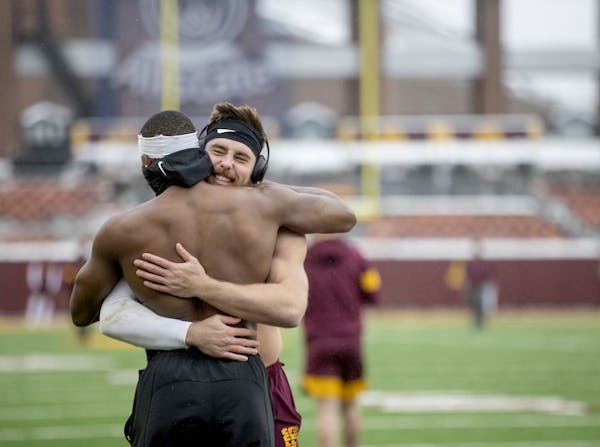 Gophers linebackers Carter Coughlin, right, and Kamal Martin, braved the cold and shared a hug while they were warming up before the Wisconsin game la