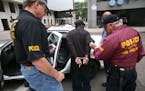 Two Metro Gang Strike Force officers searched a suspect during a major drug bust in downtown St. Paul in June 2007.