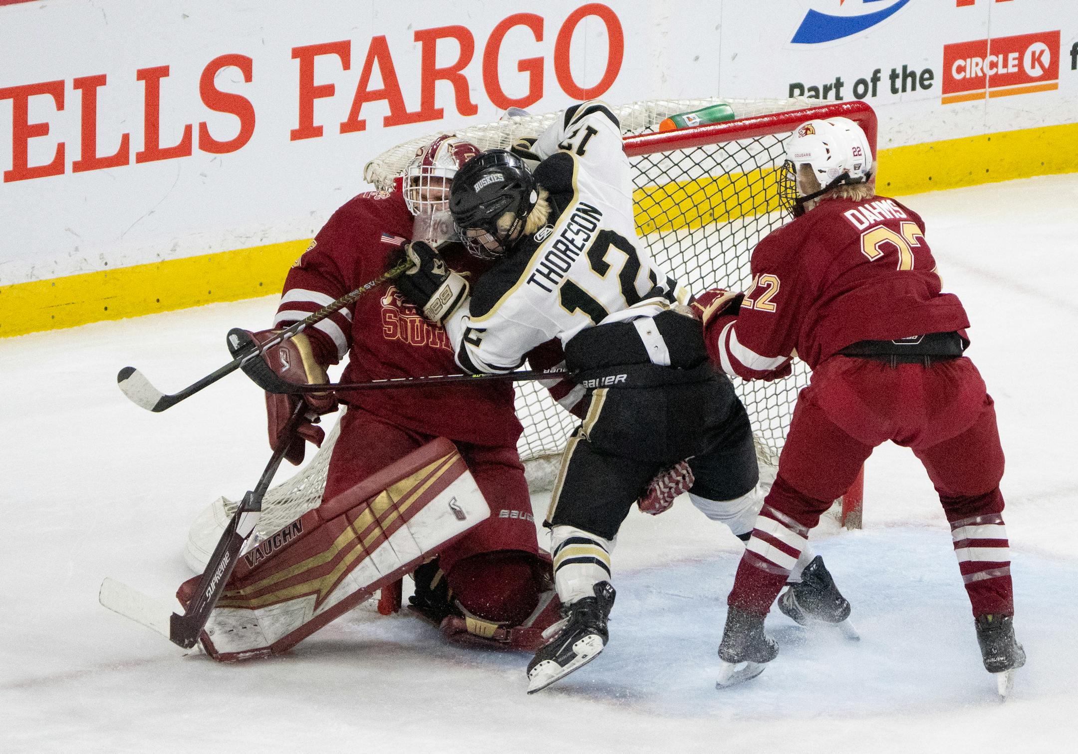 Andover Huskies forward Gavyn Thoreson (12) crashed into Lakeville South Cougars goaltender Jack Hochsprung (33) while he was defended by Lakeville South Cougars forward Ashton Dahms (22) in the first period.