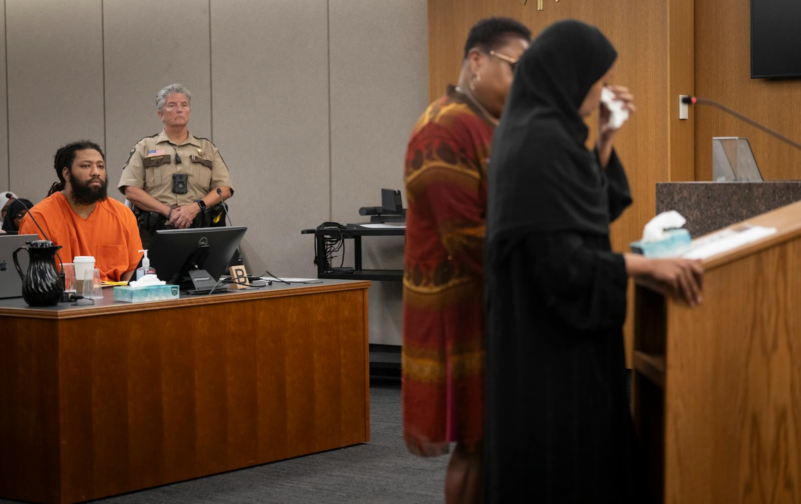 Derrick Thompson, at left, listens as Sundus Odhowa, Siham Adam’s older sister, gives an impact statement during sentencing at the Hennepin County Government Center on Thursday. 