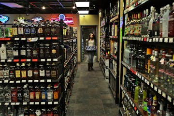 Veronica Perkins, 21, carries cans of beer while restocking the shelves at Team Liquor where she works Wednesday, Jan. 28, 2014. Perkins finishes work