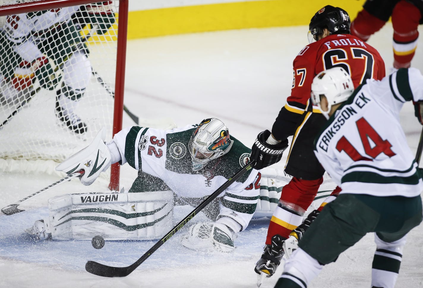 Minnesota Wild goalie Alex Stalock, left, stops Calgary Flames' Michael Frolik, center, from the Czech Republic, as the Wild's Joel Eriksson, from Sweden, watches during the first period of an NHL hockey game Saturday, Oct. 21, 2017, in Calgary, Alberta. (Jeff McIntosh/The Canadian Press via AP)