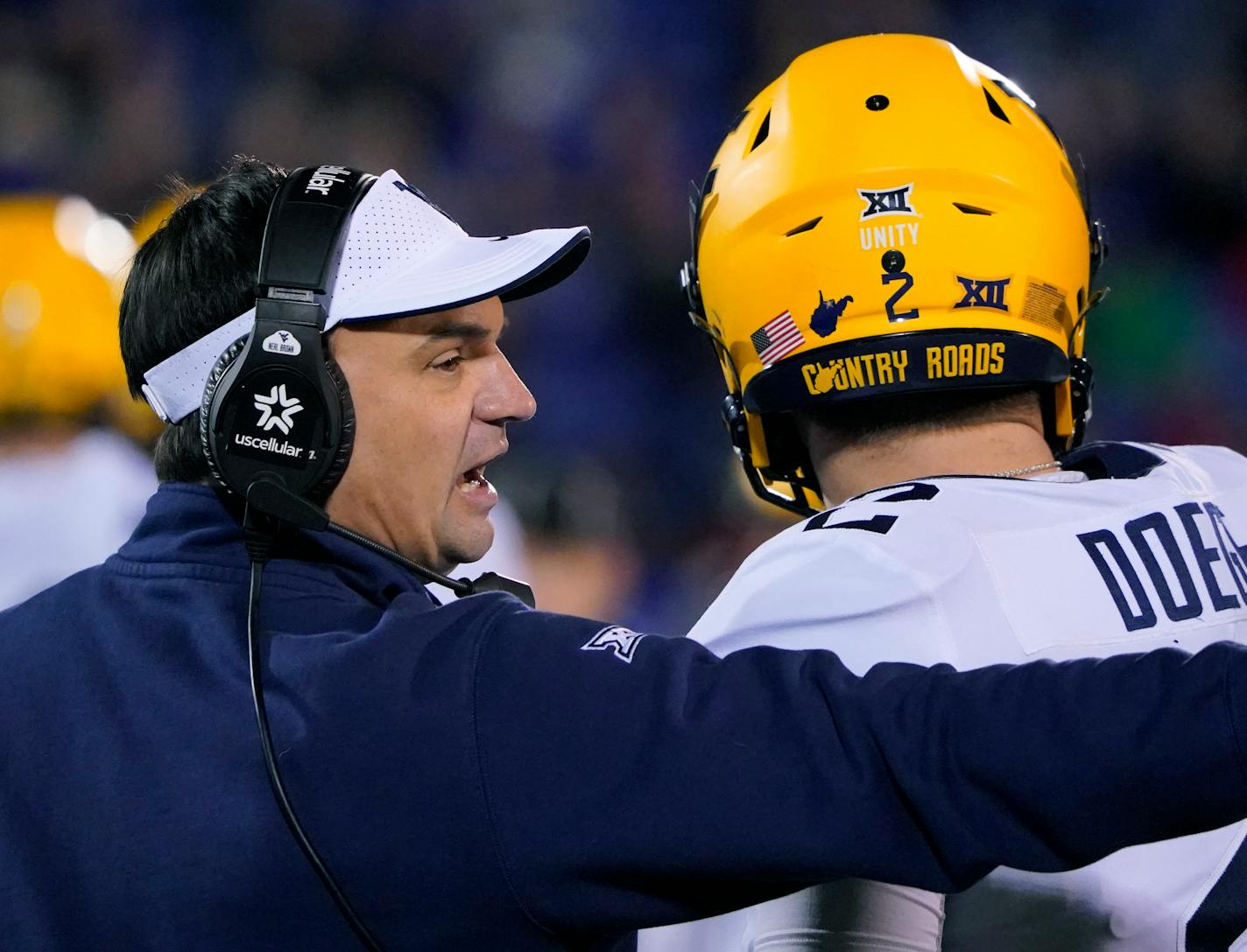 West Virginia head coach Neal Brown talks with quarterback Jarret Doege (2) during the third quarter of an NCAA college football against the Kansas game Saturday, Nov. 27, 2021, in Lawrence, Kan. (AP Photo/Ed Zurga)