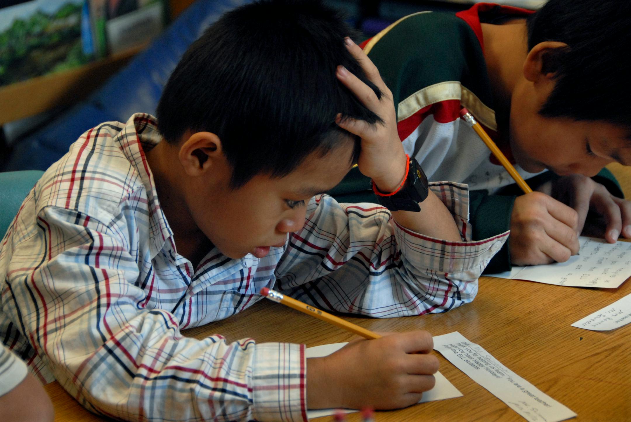 Ba Eh Hso, left, and Hsinku Lay wrote holiday cards. It was his fourth day at the school, and he was already at work copying the greeting. Many Karen students arrived in Roseville this school year with no English skills to speak of.