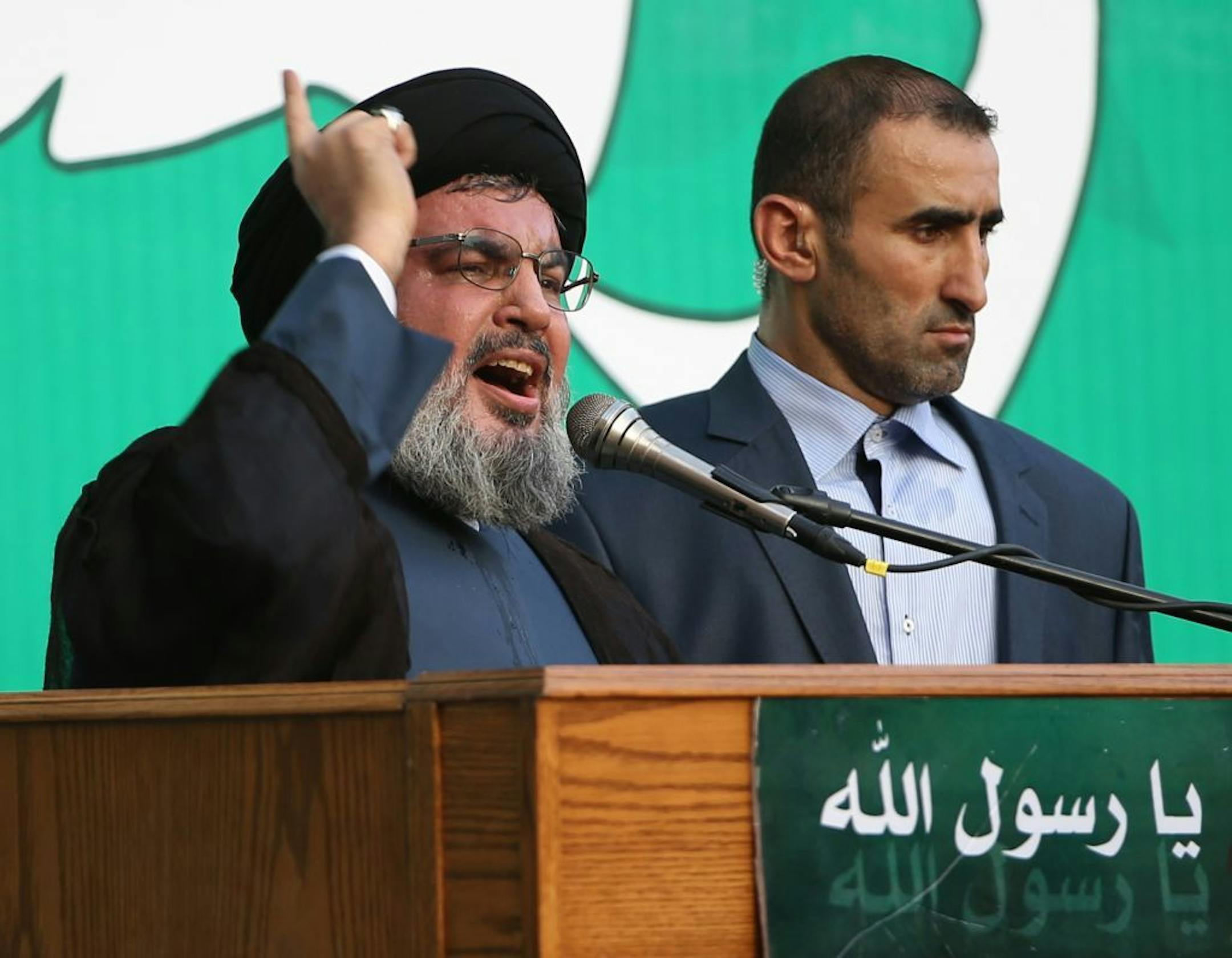 Hezbollah leader Sheik Hassan Nasrallah, left, speaks to a crowd of tens of thousands of supporters, not shown, during a rally denouncing an anti-Islam film that has provoked a week of unrest in Muslim countries worldwide, in the southern suburb of Beirut, Lebanon, Monday Sept. 17, 2012. Nasrallah who does not usually appear in public for fear of assassination called for Monday's protests in Beirut, saying the U.S. must be held accountable for the film because it was produced in America. Arabic