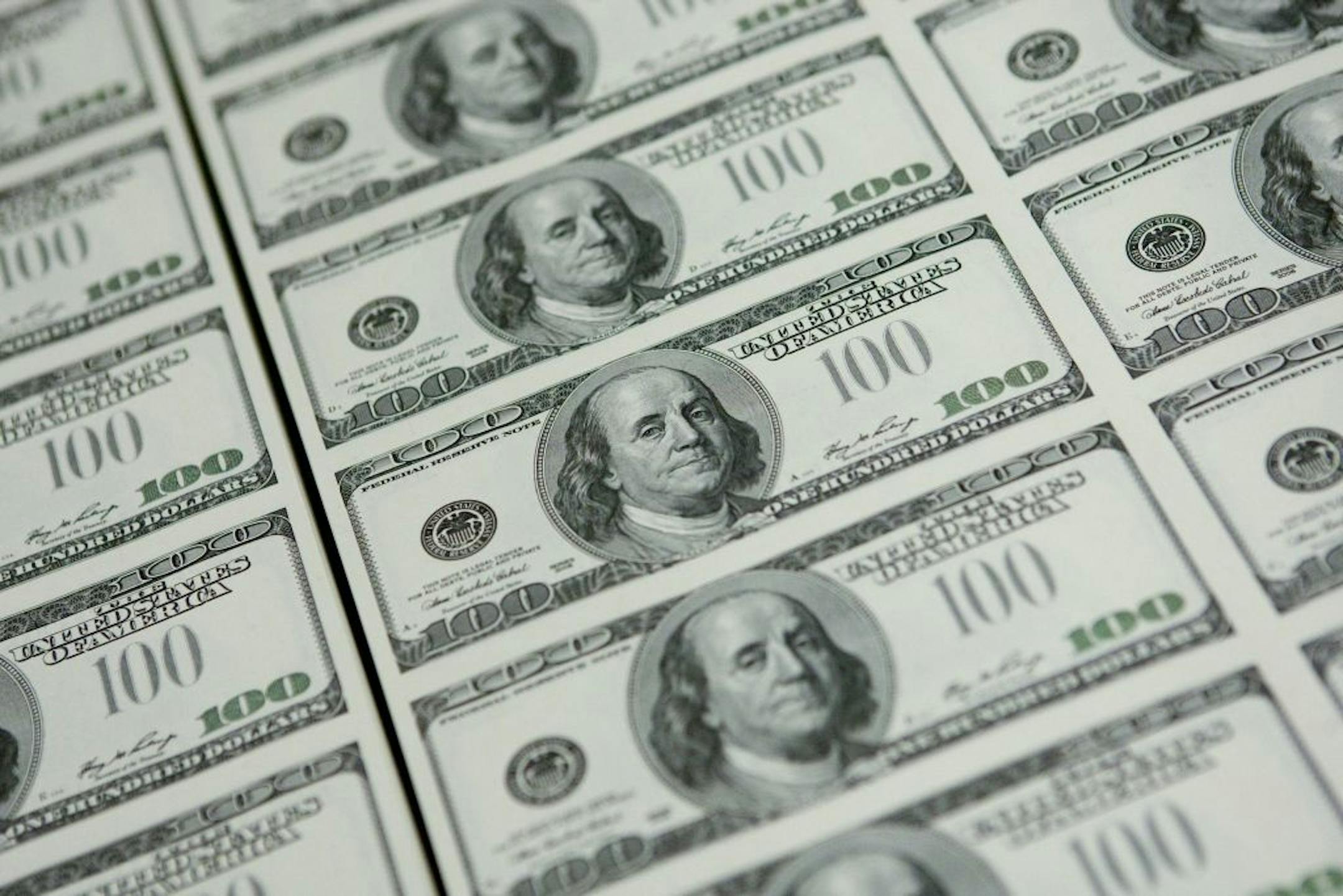 Sheets of one hundred dollar bills wait to be cut into singles at the Bureau of Engraving and Printing in Washington, D.C., U.S., on Wednesday, Oct. 14, 2009. Goldman Sachs Group Inc. said the dollar is likely to extend drops against the euro and commodity backed currencies over the coming six months, based on the greenback's correlation with cyclical assets and capital flows. Photographer: Andrew Harrer/Bloomberg