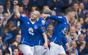 Everton's Steven Naismith, left, is congratulated by teammates after scoring his first goal against Chelsea during the English Premier League soccer m