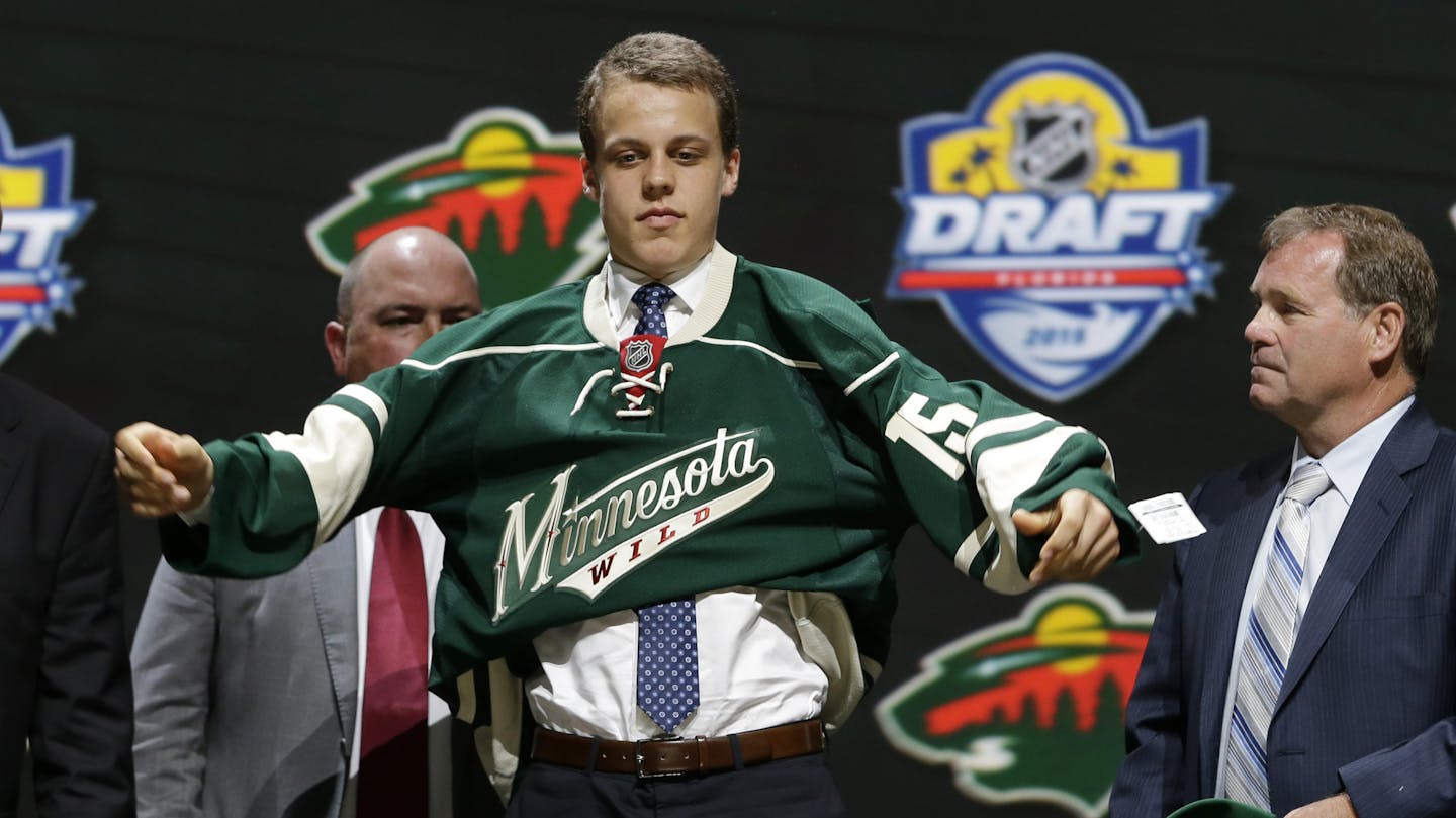 Joel Eriksson Ek, of Sweden, puts on a Minnesota Wild sweater after being chosen 20th overall during the first round of the NHL hockey draft, Friday, June 26, 2015, in Sunrise, Fla. (AP Photo/Alan Diaz)