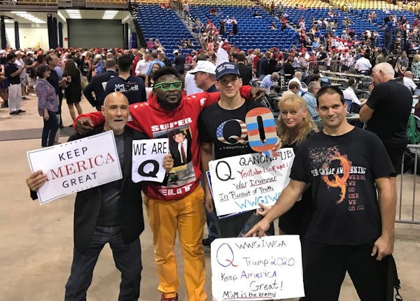 Donald Trump supporters who are proponents of the "QAnon" conspiracy theory pose for a photo after Trump spoke at a MAGA rally at the Florida State Fa