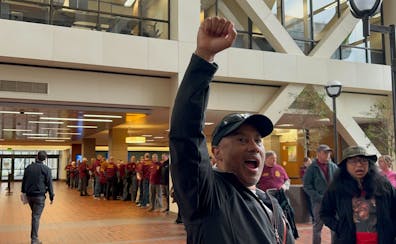 A man raises his fist demanding justice for Ricky Cobb II as supporters of Trooper Ryan Londregan look on at the Hennepin County Government Center Mon