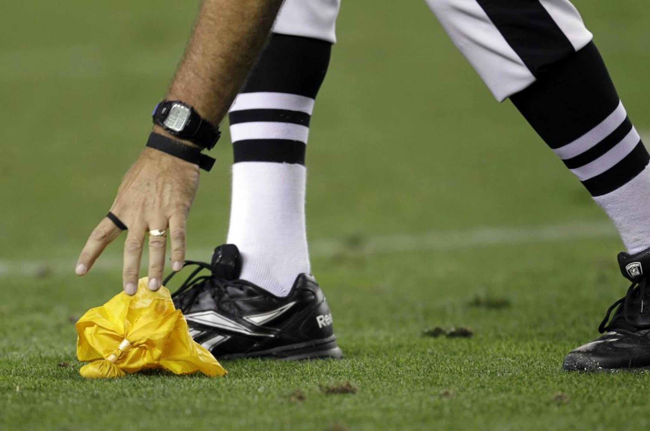 FILE - In this Sept. 12, 2011, file photo, an official picks up a penalty flag during an NFL football game between the Oakland Raiders and Denver Broncos, in Denver. From unfocused pre-snap penalties to overaggressive personal fouls to garden-variety holds, Oakland is committing penalties at an unprecedented rate. With four infractions for 11 yards in the season finale, the Raiders will set records for penalties and penalty yards in a season.