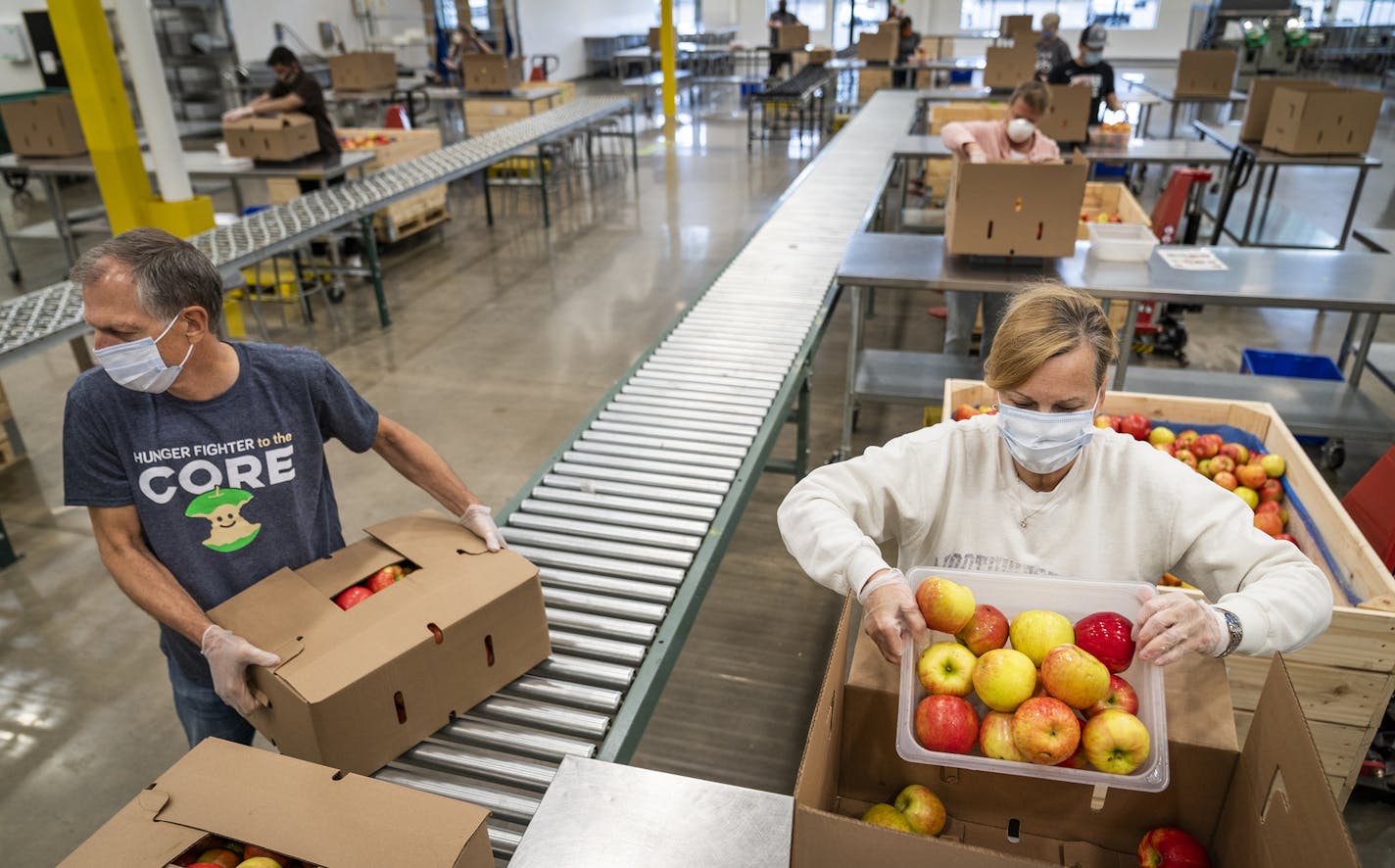 Volunteers Mark Lewry and his wife Jean Lewry of Greenwood packed apples at Second Harvest Heartland in Brooklyn Park. ] LEILA NAVIDI • leila.navidi@startribune.com BACKGROUND INFORMATION: Volunteers pack apples into boxes at Second Harvest Heartland in Brooklyn Park on Friday, May 22, 2020. Second Harvest Heartland has long relied on hundreds of volunteers to pack food that's distributed to food shelves. But with COVID-19, the food bank has had a big drop in the number of volunteers because it'