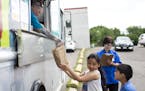 Erin George hands children a free lunch from the Summer Food Service Program truck at a St. Paul apartment complex. ] NICOLE NERI &#xa5; nicole.neri@s